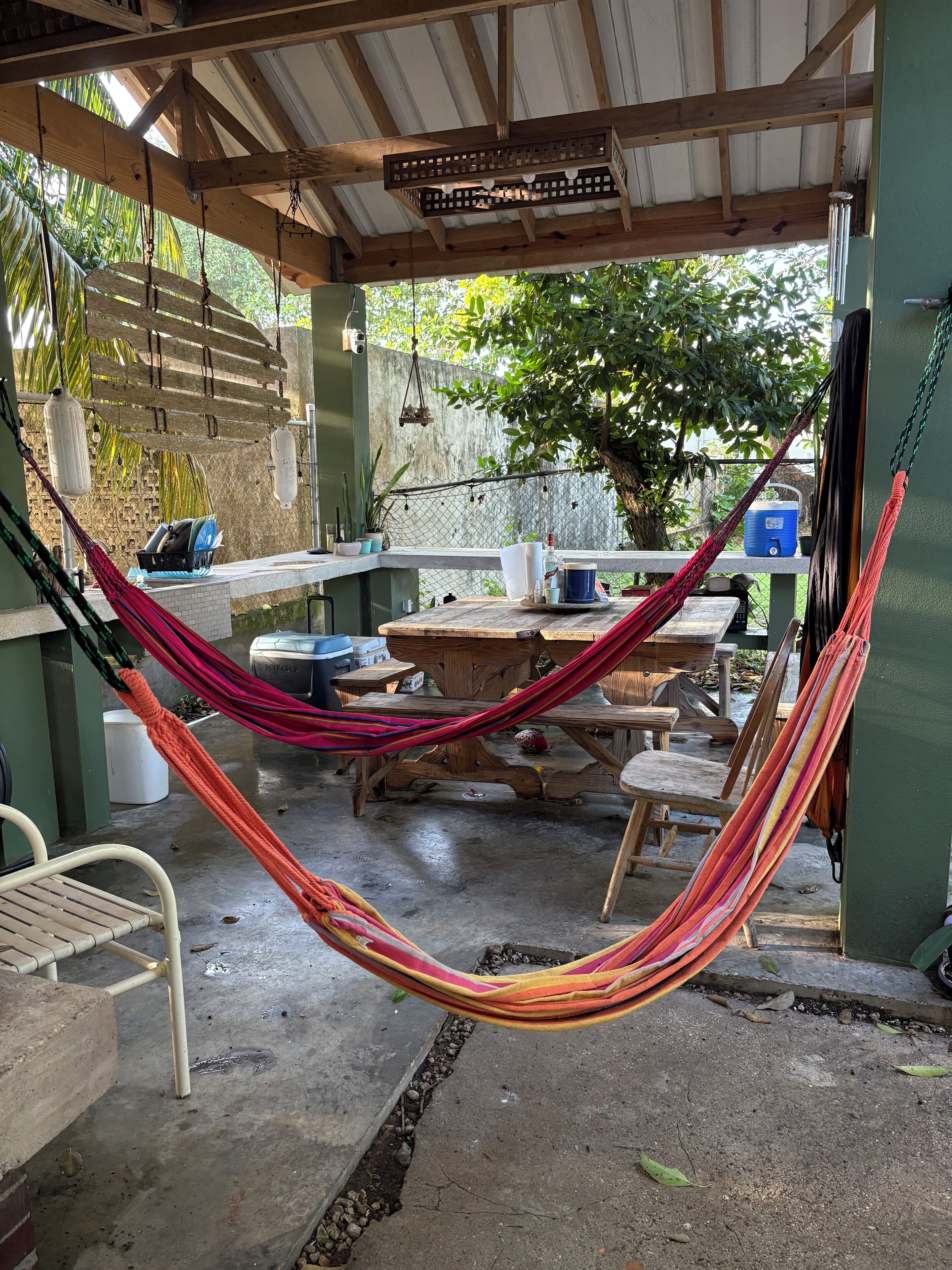 Un espace extérieur abrité comprenant un hamac, des meubles en bois et une table.
