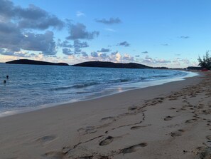 A beach with footprints in the sand, a calm sea, and distant hills. - Second Story Beach Unit, Three Bedrooms, One Baths, Sleeps up to 4 guests
 (Vega Baja)