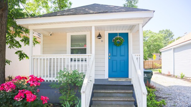 A house with a blue front door, a porch with a white railing, and a 'Private Property' sign.