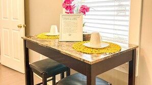 A dining table with a framed menu, two chairs, and a vase of flowers.