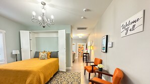 A bedroom with a bed, a chair, a rug, and a 'Welcome' sign.