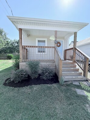 A two-story house with a covered porch, a front door, and a staircase leading to the upper level.