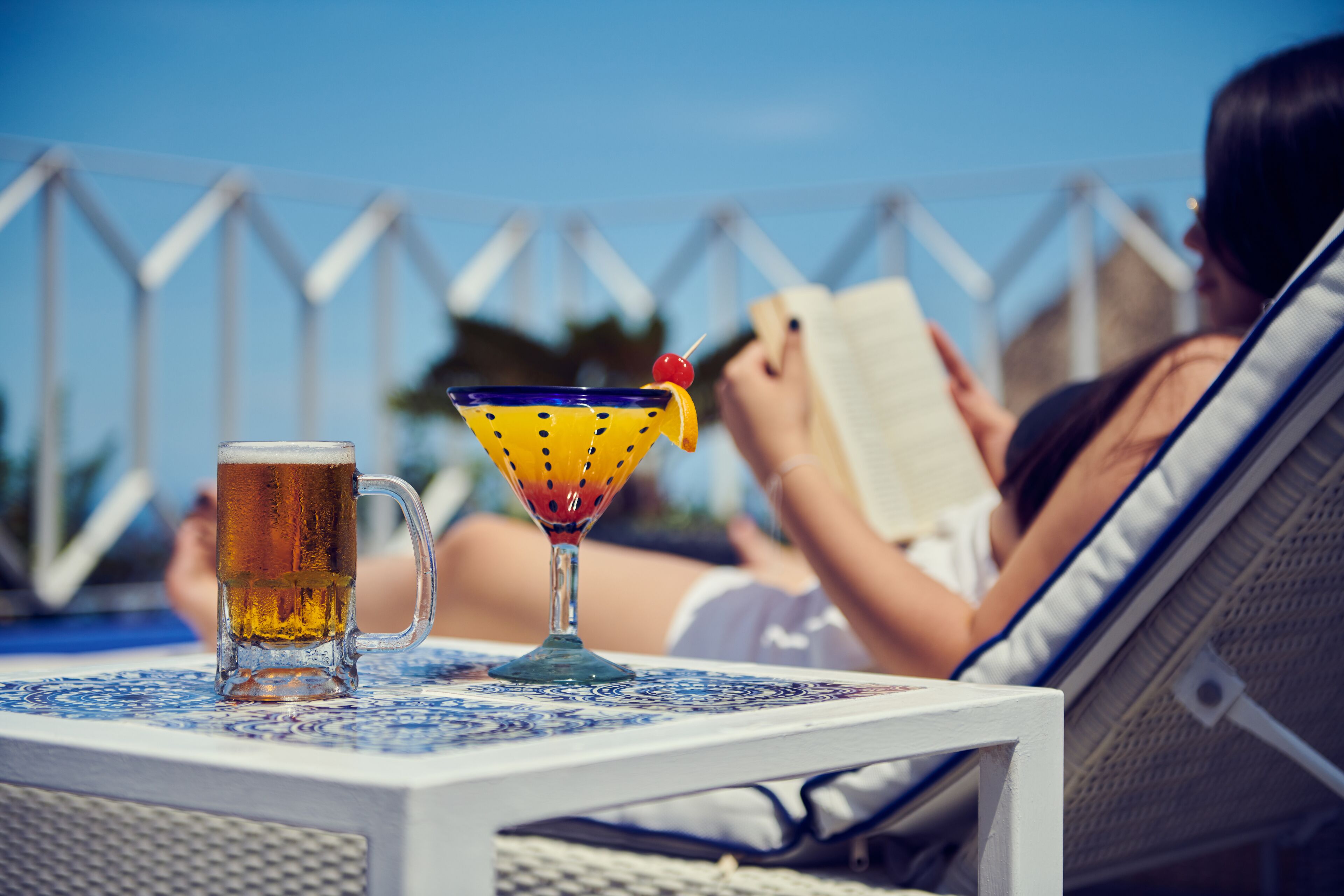 Eine Person entspannt an einem Pooltisch mit einem Bierkrug und einem Cocktailglas.