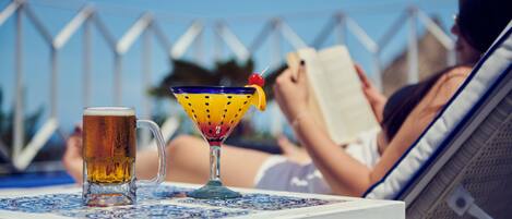 Eine Person entspannt an einem Pooltisch mit einem Bierkrug und einem Cocktailglas.