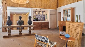 Eine Lobby mit Holzboden, einer Rezeption, einem gemusterten Sessel und einem Rattan-Sessel.