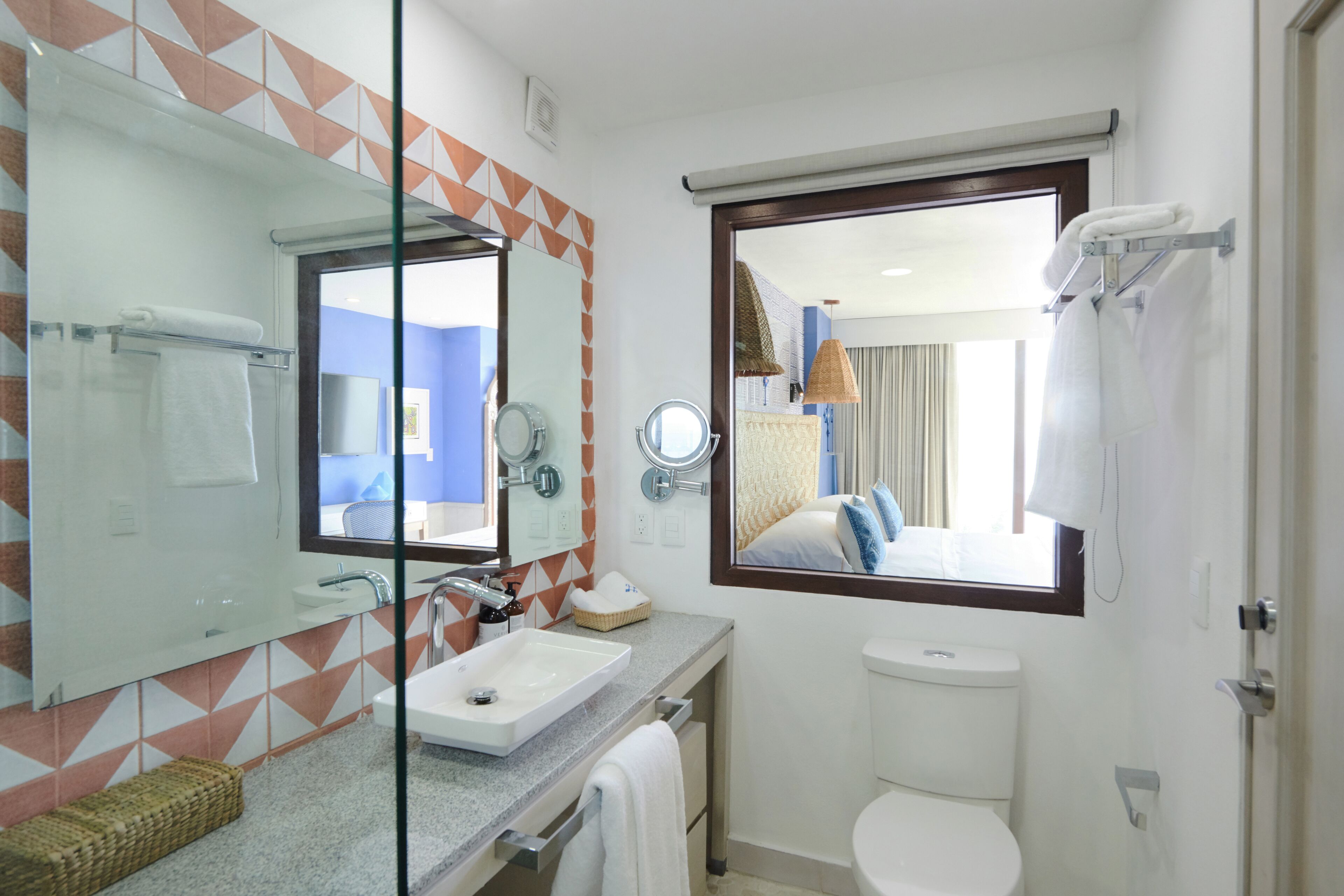 A modern bathroom with a glass shower enclosure, a sink, a toilet, and a large mirror.