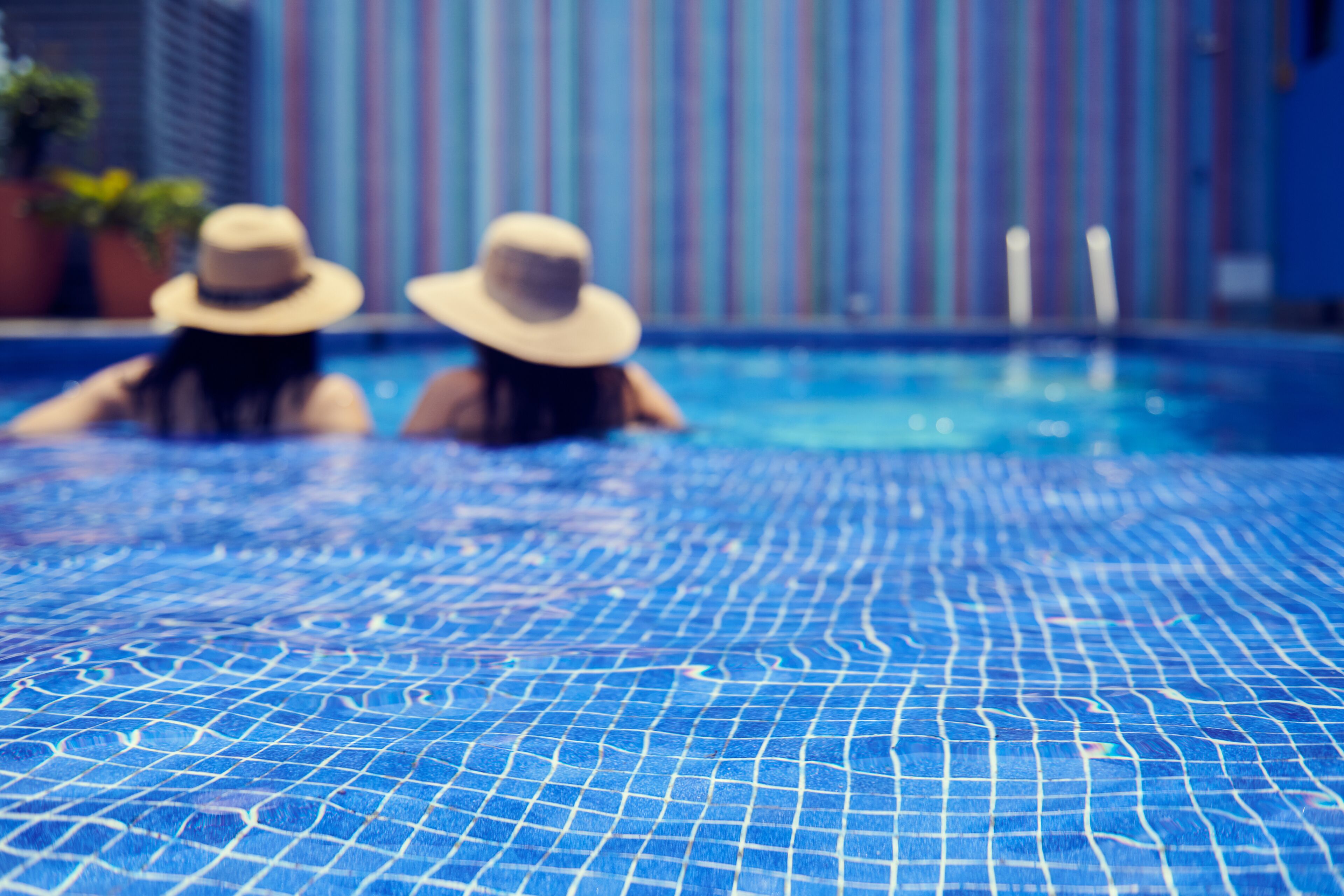 Une piscine avec un sol carrelé et un mur à rayures en arrière-plan.