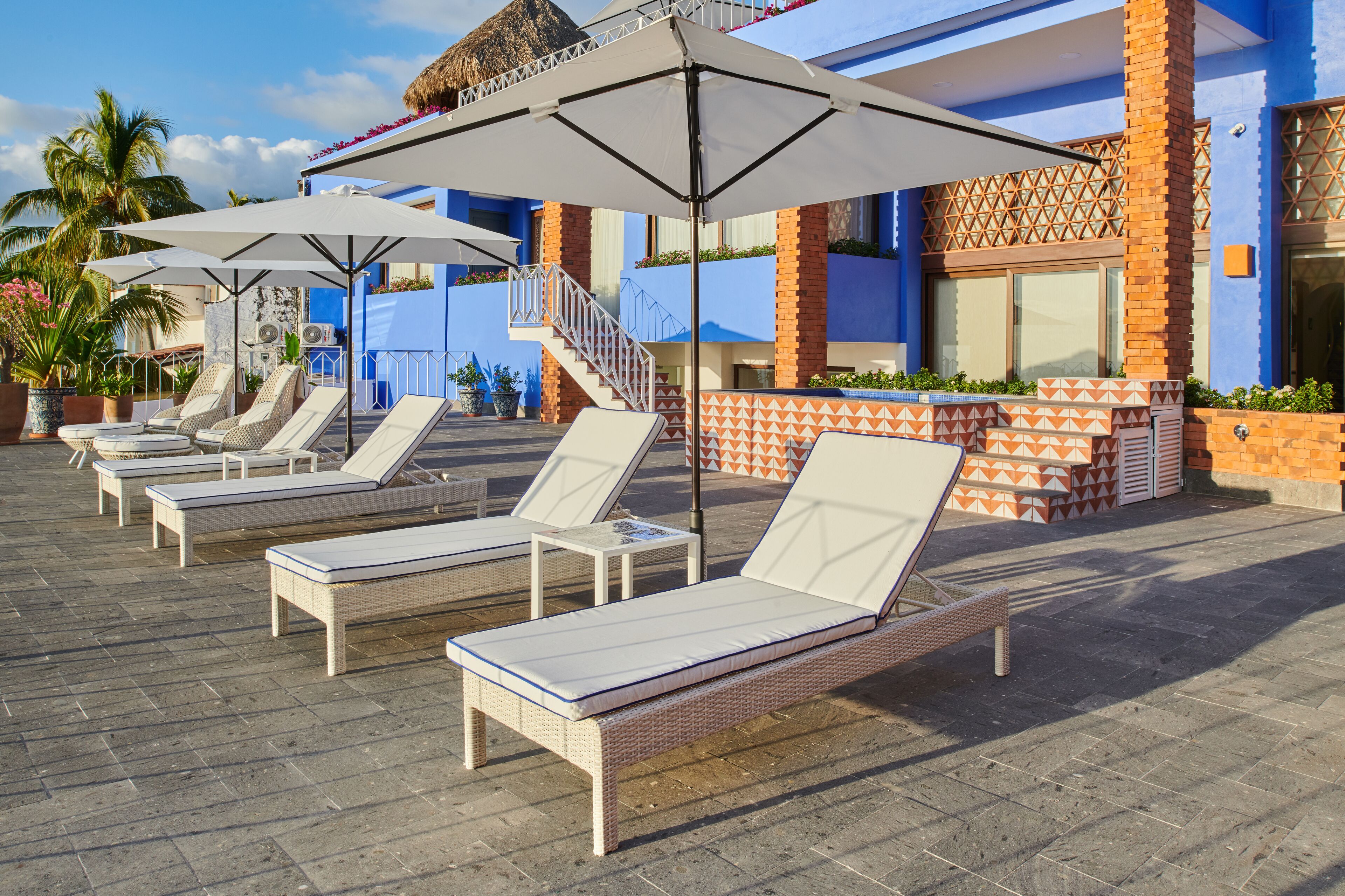 A rooftop pool area with lounge chairs and umbrellas.