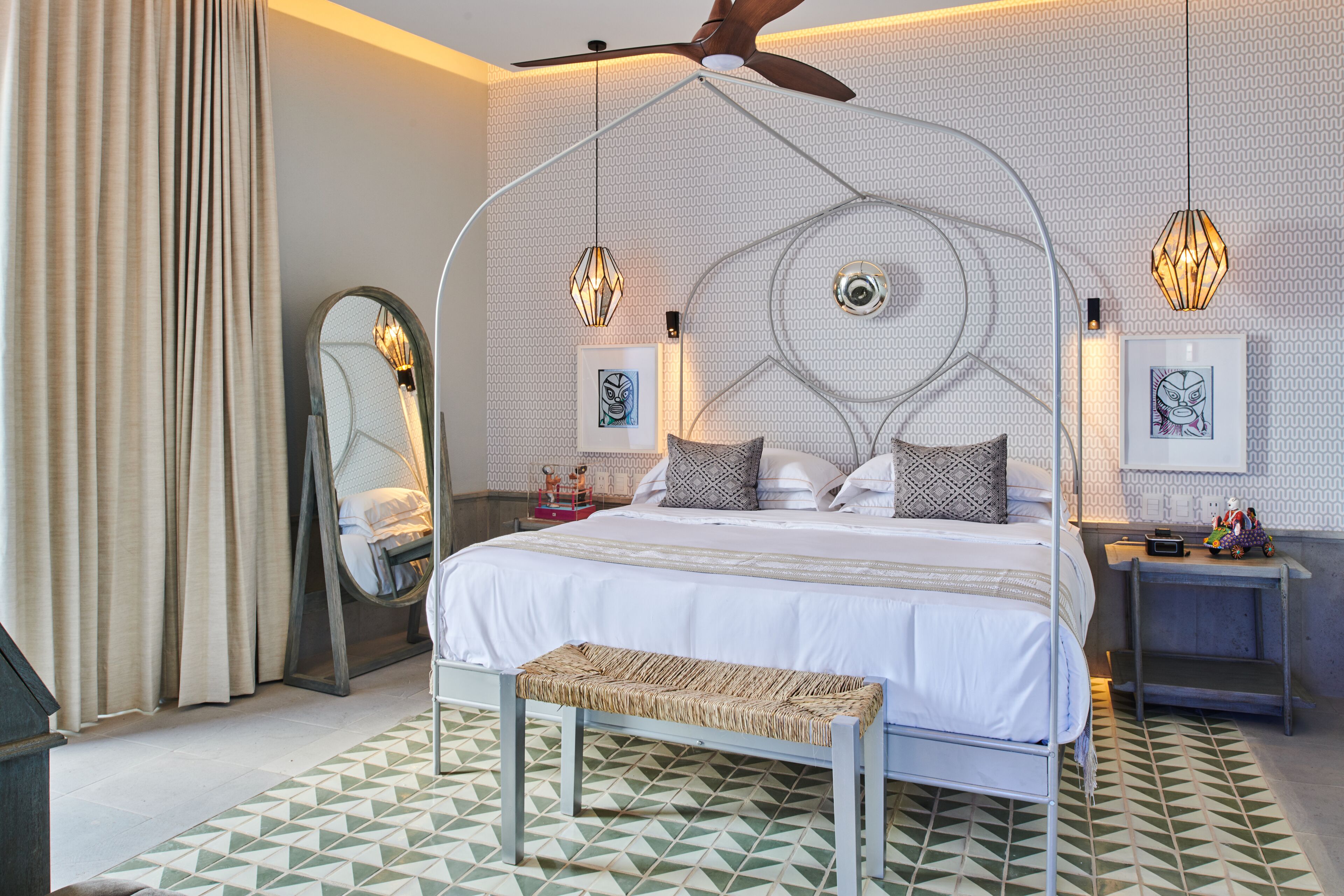 Un dormitorio moderno con una cama, un banco, un ventilador de techo y luces decorativas.