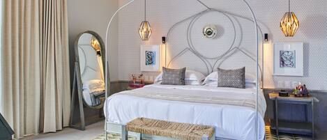 Un dormitorio moderno con una cama, un banco, un ventilador de techo y luces decorativas.