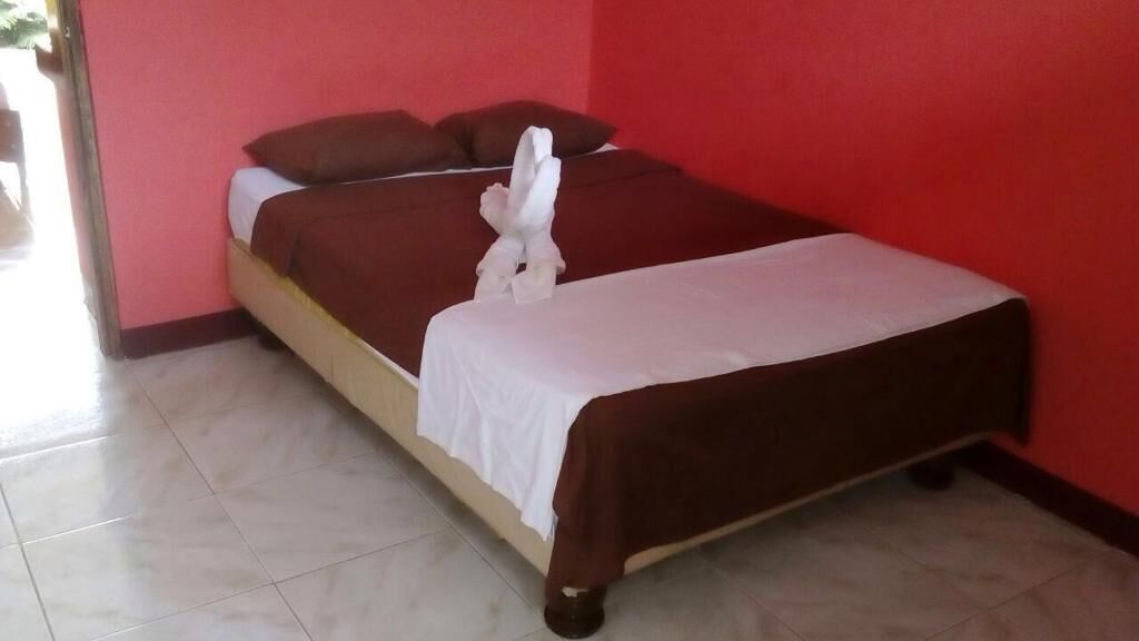 Ein Einzelbett mit braunem Kopfteil und Fußteil, weißer Bettwäsche und einem dekorativen Handtuch auf dem Fußteil.