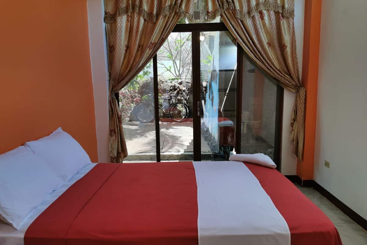 Habitación de hotel con una cama, puerta corredera de vidrio que da a un espacio exterior y vistas al exterior.