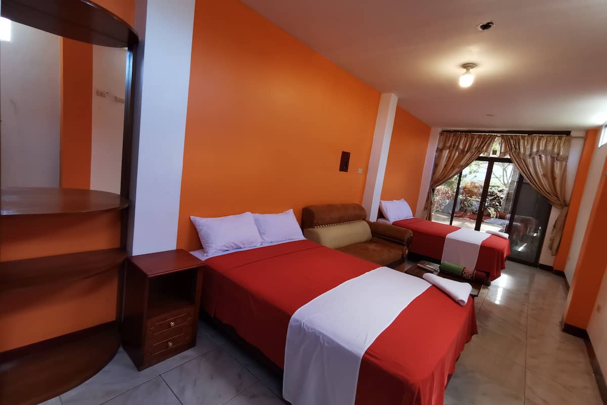 Una habitación de hotel con cama, sofá, una mesita y ventana con cortinas.