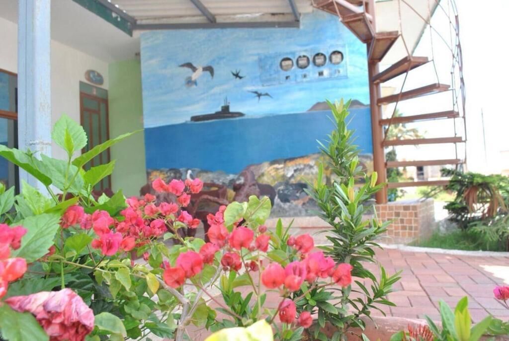 Un mural que muestra aves volando sobre el agua, con un barco, una escalera y la fachada de un edificio.