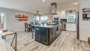 Una cocina moderna con una isla central, electrodomésticos de acero inoxidable y un amplio ventanal que proporciona luz natural.
