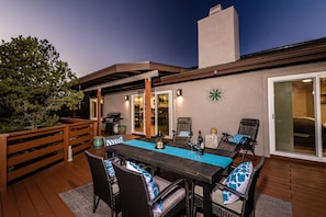 An outdoor patio with a dining table and chairs, a grill, and a decorative wall piece.