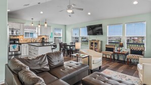 A spacious living area with a brown leather sofa, a dining table with chairs, and a kitchen in the background. - The Sea Turtle, Family and Dog Friendly, Cargo Lift, Crystal Beach TX Ocean View (Bolivar Peninsula/Crystal Beach)
