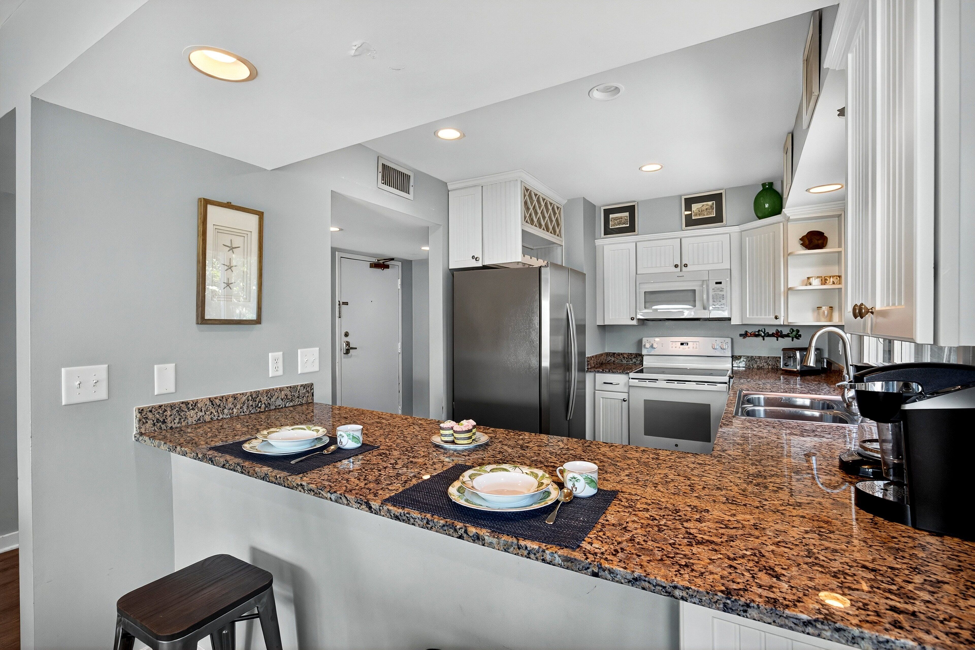 A modern kitchen with granite countertops, stainless steel appliances, and white cabinetry.