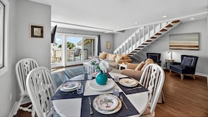 A dining area with a table set for four, a sofa, and a staircase. - PRIME Resort Location! Beachside, Ocean View, Pool Access! (Isle Of Palms)