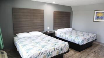 Une chambre d’hôtel avec deux lits, chacun agrémenté d’une literie à motifs, d’une table de chevet et d’un luminaire fixé au mur.