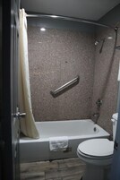 Un baño moderno con bañera, ducha e inodoro.