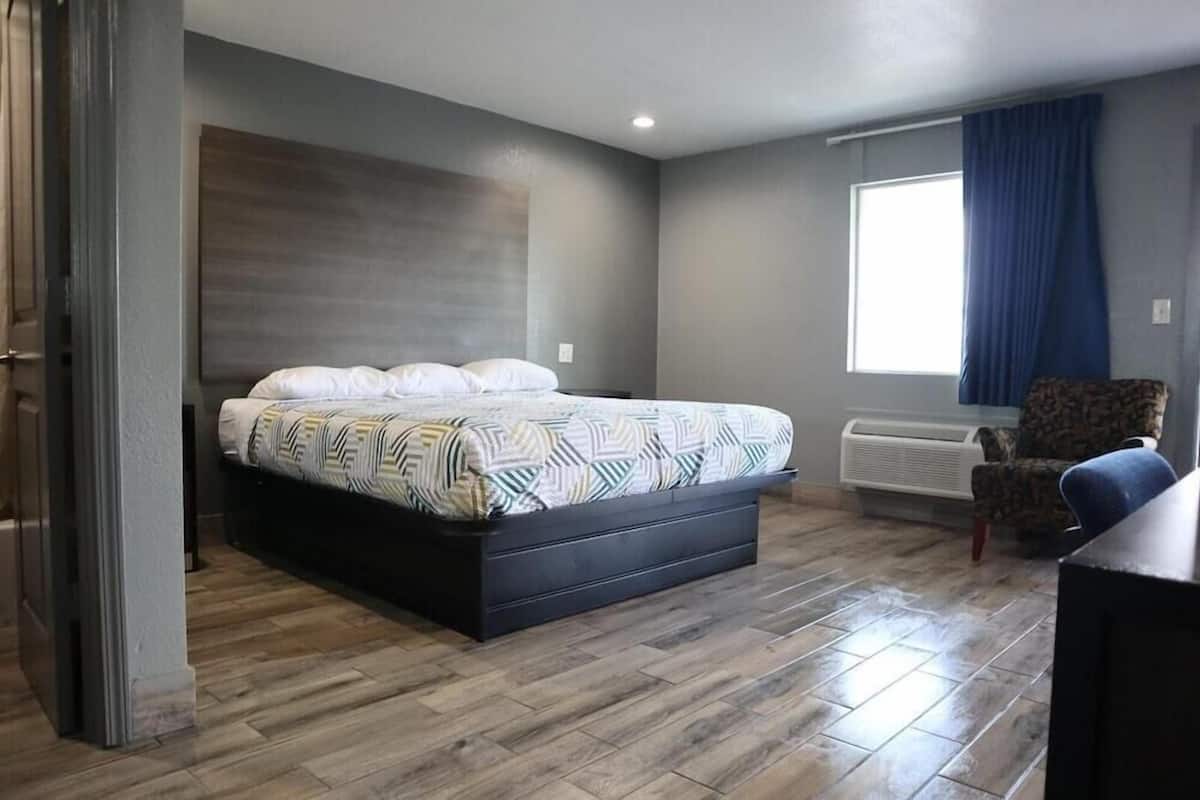 Quarto com cama, cadeira, janela e aquecedor fixado na parede.