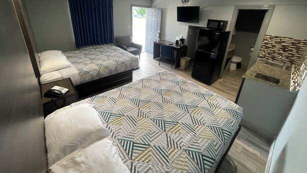 Een kleine hotelkamer met twee bedden, een bureau, een stoel, een televisie, een koelkast en een magnetron.