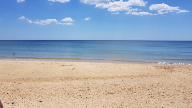 A beach with a clear sky and calm sea.