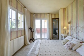 Ein Schlafzimmer mit einem großen Bett, einem Nachttisch mit Lampe, einer Heizung und Blick durch eine Glastür nach draußen.