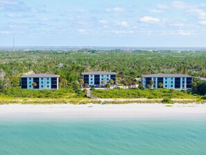 Una propiedad frente a la playa con tres edificios modernos, una playa arenosa y vista al océano.