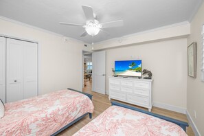 A bedroom with two beds, a ceiling fan, a TV, and a dresser. - Luxury Two Bedroom Gulf Front Condo! Amazing Location & Condo! Tarpon Beach 104 (Sanibel)