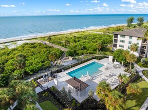 Un complexe hôtelier doté d’une piscine, offrant une vue sur la plage et comprenant un jardin aménagé.