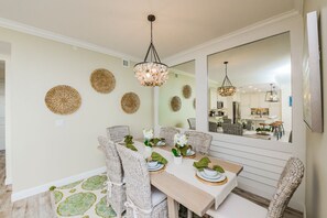 Un coin repas avec des chaises en osier, une table en bois et un lustre.