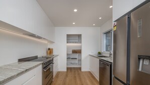 A modern kitchen with white cabinetry, a stainless steel refrigerator, and a wooden floor.
