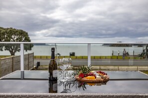 Ein Tisch mit einer Weinflasche, einem Glas sowie einer Holzplatte mit Käse und Trauben.