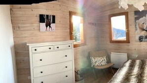 A cozy wooden cabin bedroom with a bed, dresser, chair, and two windows offering views of the outdoors. - Nice Chalet LEON located in Plangagnant (1650 m) La PLAGNE - LA ROCHE chairlift (Plangagnant)