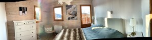 Accogliente camera da letto in una baita di legno, con un letto, una cassettiera, una sedia e due finestre che offrono vista sull'esterno.