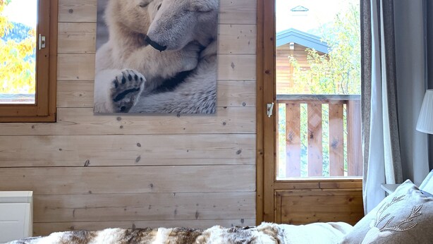 A cozy room with wooden walls, a large window, and a bed with a furry blanket. - Nice Chalet LEON located in Plangagnant (1650 m) La PLAGNE - LA ROCHE chairlift (Plangagnant)