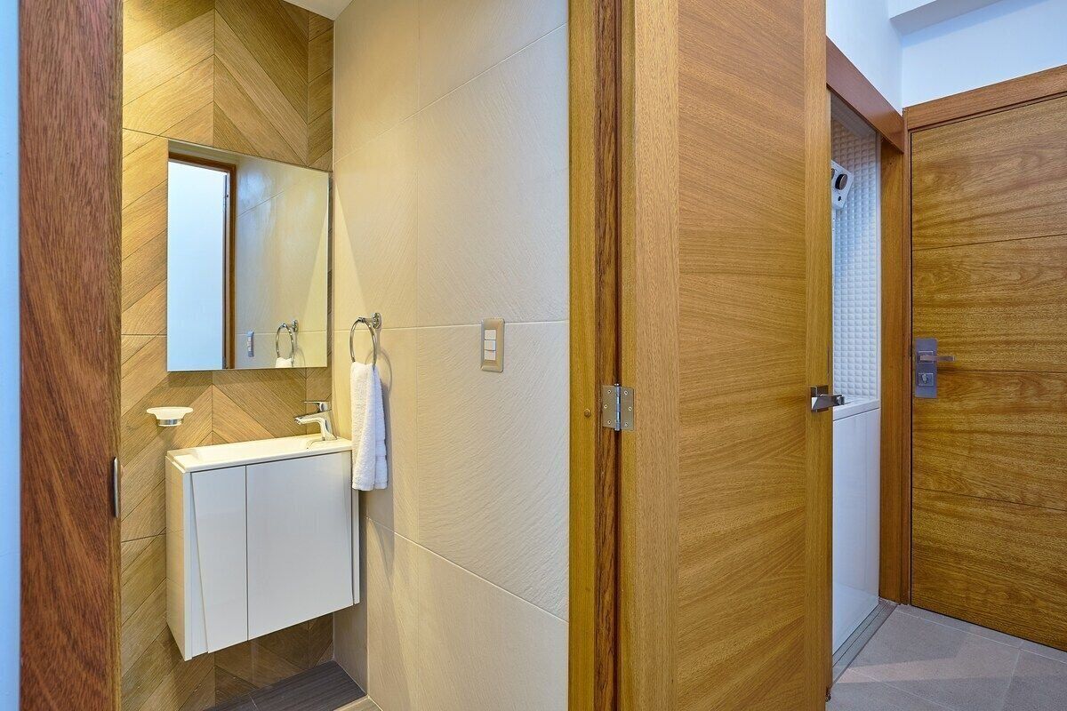 A modern bathroom with a wooden vanity, a mirror, and a shower area.