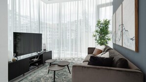 Una sala de estar moderna con un televisor grande, un sofá, una mesa de centro y una planta.