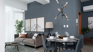 Un comedor moderno con un sofá gris, una mesa de comedor dispuesta con platos y vasos, y una lámpara original arriba.