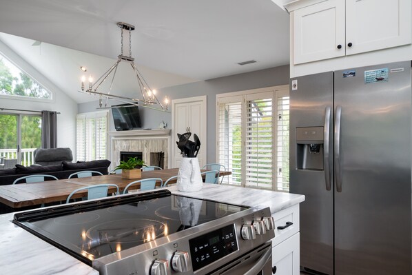 A modern kitchen with a stainless steel refrigerator, a built-in oven, and a large island with a stovetop.