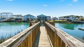 A wooden pier leading to a marina with houses on the other side. - High Tide - A Fisherman's Delight:  4 BR Channel Home w/ Boat Ramp in Cherry Grove (North Myrtle Beach)