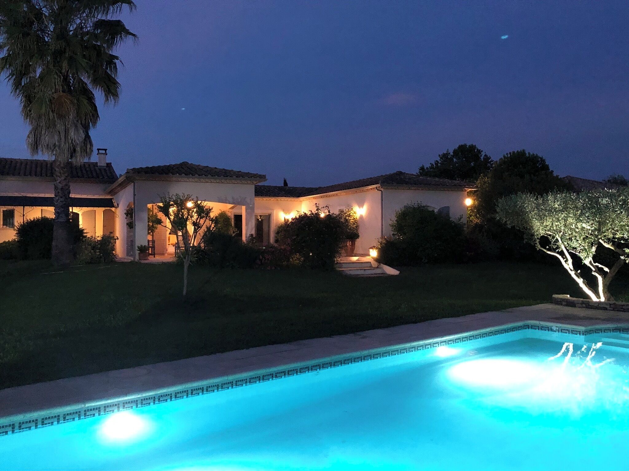 Propiedad residencial con piscina, zona de patio y entrada bien iluminada.