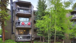A multi-story building with balconies, outdoor seating, and a grassy area with trees. - New Listing! Strike Gold at this Prime Location - Bus Route-Fast WiFi (Breckenridge)
