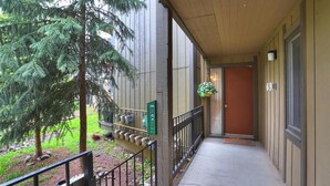 A covered outdoor corridor with a metal railing, a green sign, and a hanging planter. - New Listing! Strike Gold at this Prime Location - Bus Route-Fast WiFi (Breckenridge)
