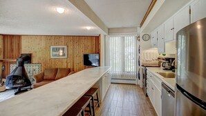 A kitchen with wooden panel walls, a long counter, a stove, and a refrigerator. - New Listing! Strike Gold at this Prime Location - Bus Route-Fast WiFi (Breckenridge)