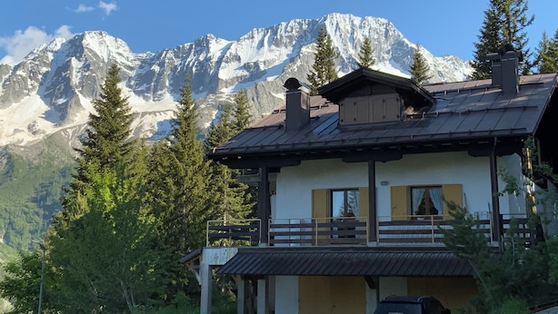 A chalet with a balcony overlooking a snowy mountain range.