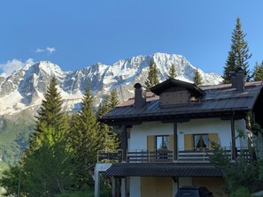Un chalet doté d’un balcon donnant sur une chaîne de montagnes enneigées.