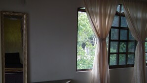 A room with a large mirror, a small table, and a window with curtains.